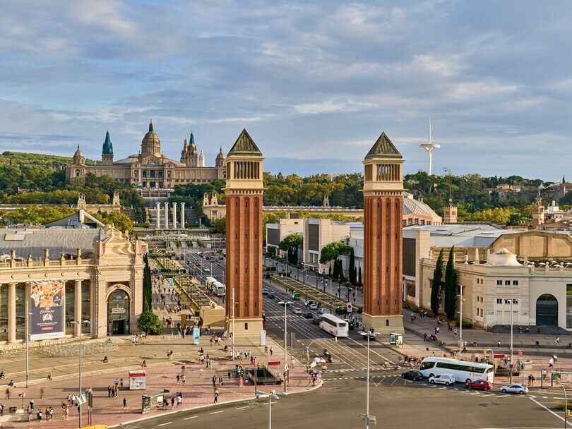 Vista panorámica de la plaza y edificios históricos, con torres altas, calles y cielo nublado.