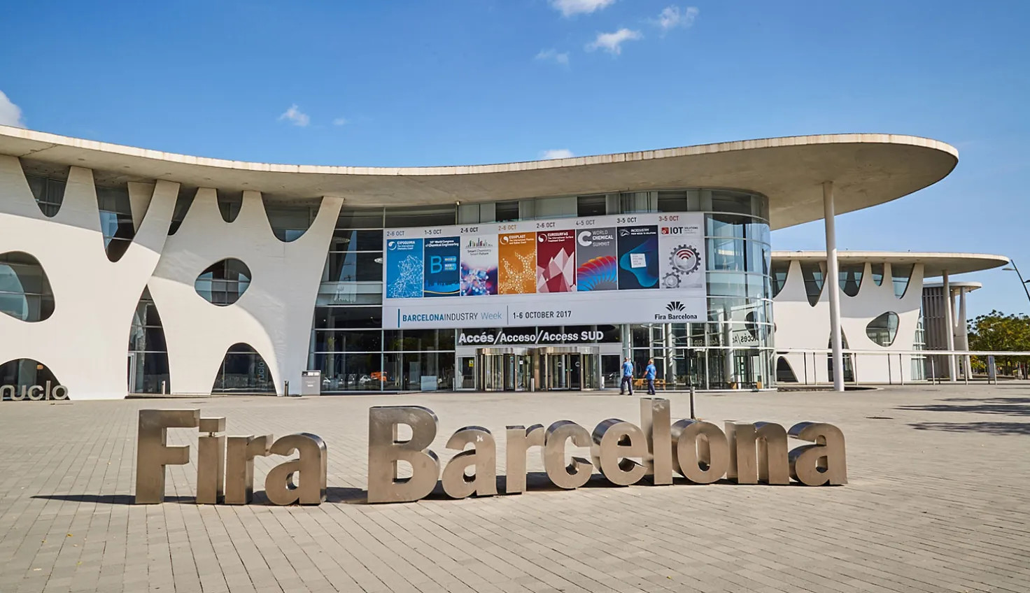Fachada moderna de la Fira Barcelona con letras metálicas “Fira Barcelona” y carteles de evento.